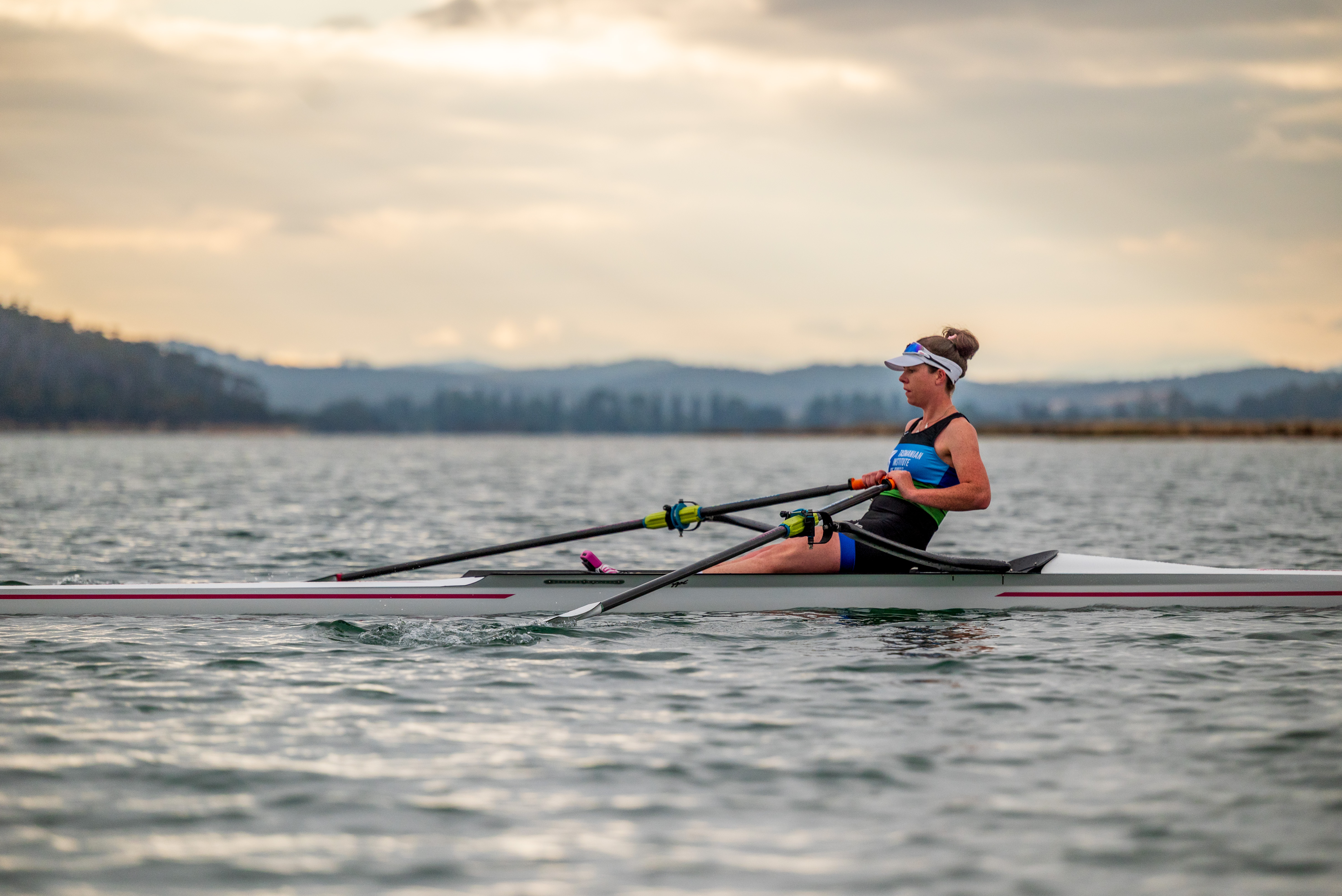 Ella Marshall in a single rowing shell, on the water at Mersey River at Sunrise